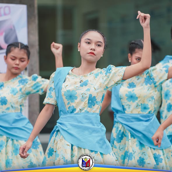 Mga kababaihang nagsasayaw ng folk dance na naka-floral na bestida sa labas ng gusali sa Naic