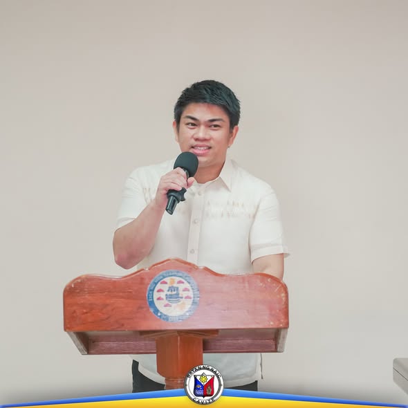 Lalaking nagsasalita sa mikropono sa podium sa isang programa ng Naic, Cavite