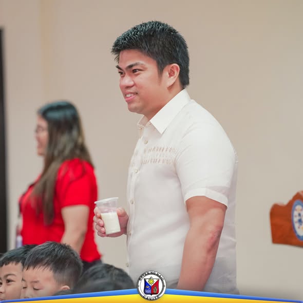 Litrato: Lalaking nakatayo na may hawak na baso ng gatas habang nasa Milk Feeding Program sa Naic