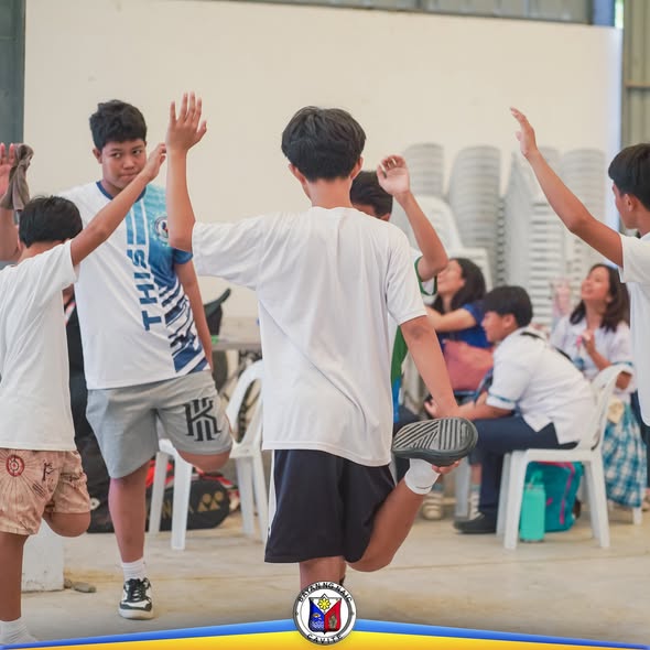 Mga kabataang lalaki na nag-iinat at nagse-warm up sa loob ng gym habang nagsisimula ang Municipal Meet 2025