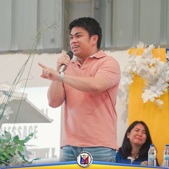 Isang lalaking nagsasalita sa mikropono habang nagtuturo sa event ng Hataw Naicqueño 2025, may puting dekorasyon sa likod