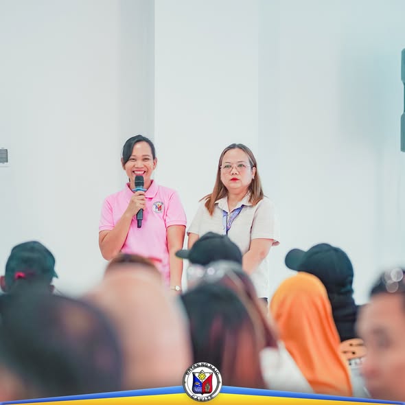 Babaeng nagsasalita gamit ang mikropono sa harap ng mga dumalo sa pagpupulong ng Local Development Council