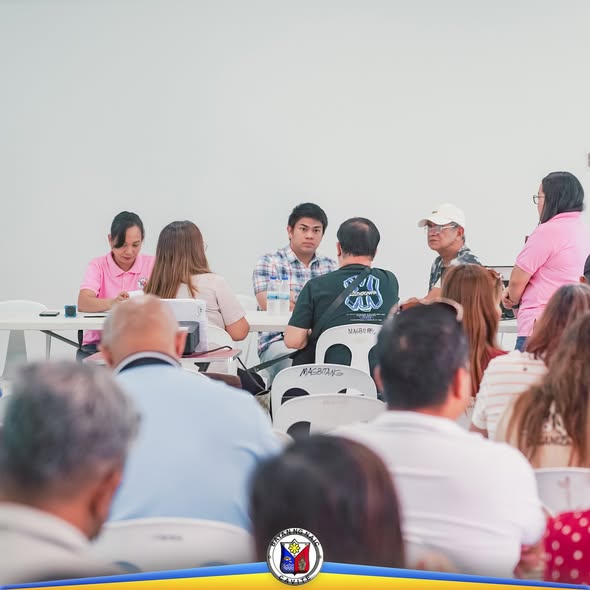 Mga kalahok sa pagpupulong ng Local Development Council na nakaupo sa paligid ng mesa sa loob ng hall sa Naic