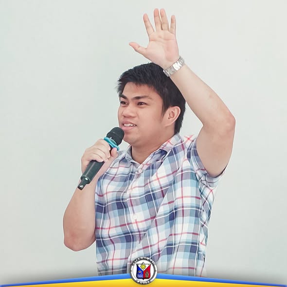Lalaking nagsasalita sa mikropono habang nakataas ang kamay sa pagpupulong ng Local Development Council sa Naic