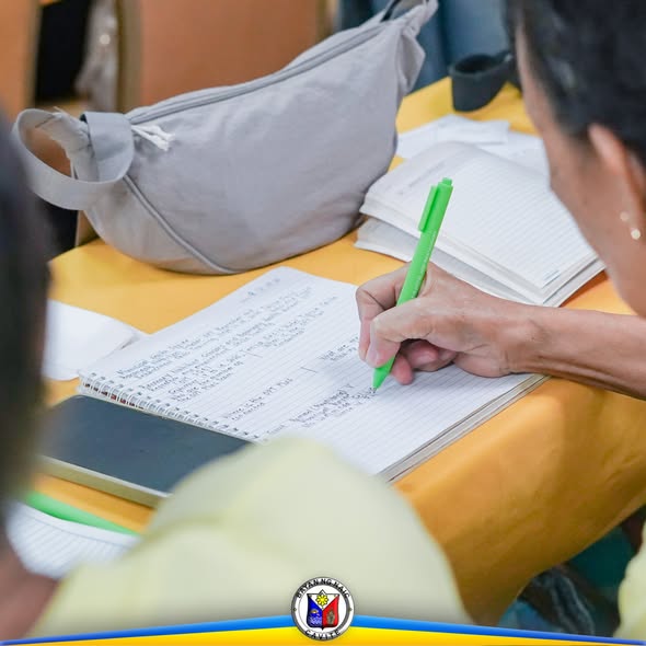 Babaeng nagsusulat sa notebook gamit ang berdeng ballpen sa training ng mga BNS sa Naic