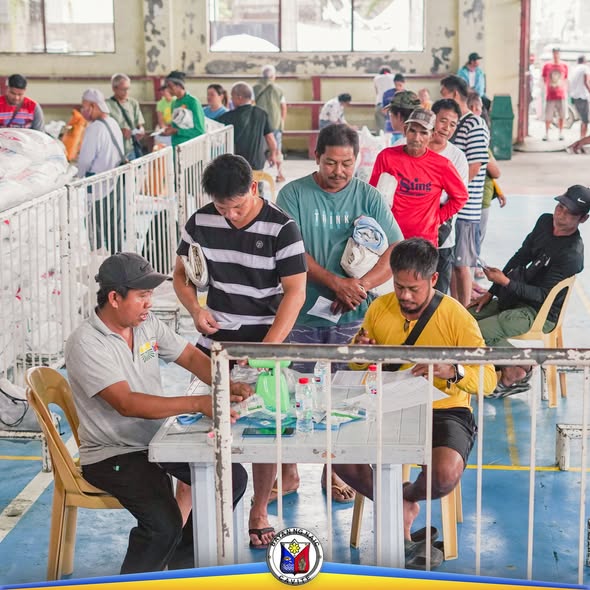 Mga magsasaka na pumipila para sa distribusyon ng fertilizer sa covered court ng Naic