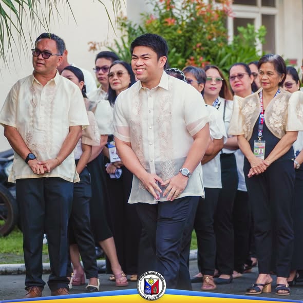 Mga kawani ng Lokal na Pamahalaan ng Naic na nakatayo at nakikinig sa flag-raising ceremony