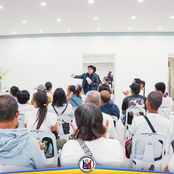 Isang tagapagsalita na nagsasalita sa harap ng mga nakaupong dumalo sa loob ng puting silid