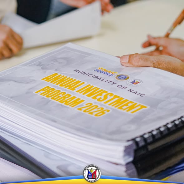 Poster: Annual Investment Program 2026, Municipality of Naic, nakalagay sa tambak na dokumento sa mesa