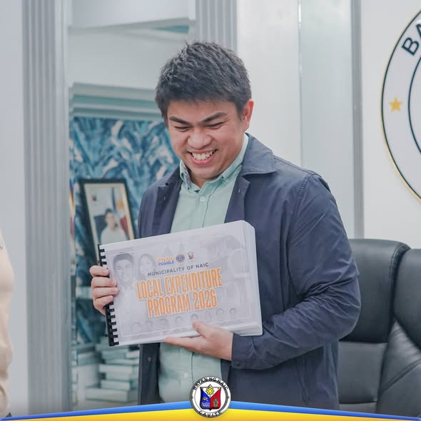 Lalaking nakangiti habang hawak ang Local Expenditure Program 2026 sa loob ng opisina ng Naic