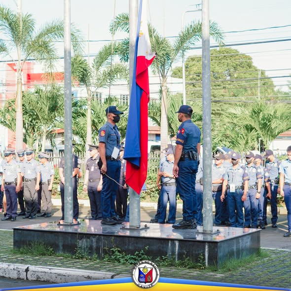 Mga uniporme na kawani habang itinataas ang watawat sa flag-raising ceremony sa Naic Municipal Hall