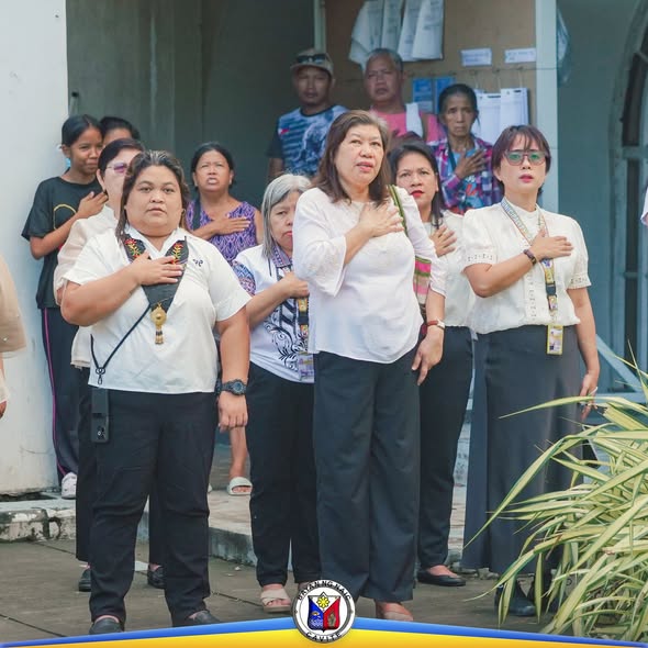 Mga kawani ng BPLO na nakatayo at nakahawak sa dibdib habang nagfa-flag ceremony sa Naic Municipal Hall