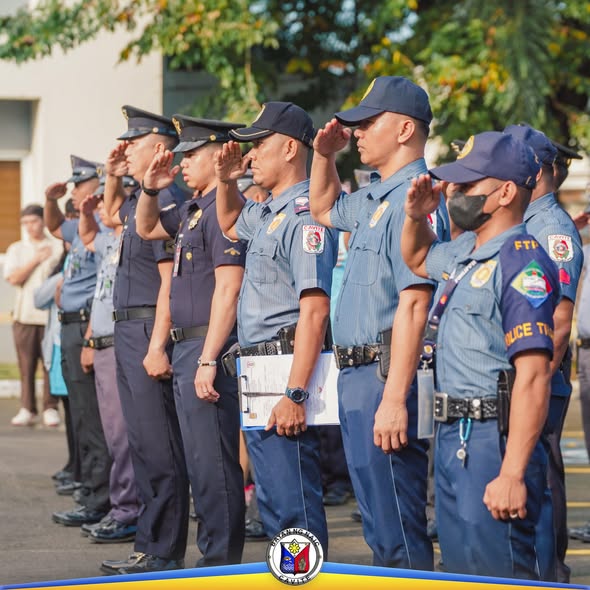 Mga uniporme ng pulis na nagsasaludo habang nasa flag-raising ceremony sa labas ng Naic Municipal Hall