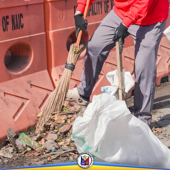 Road clearing: nagwawalis ng basura at dahon sa kalsada malapit sa mga orange na barrier ng Naic