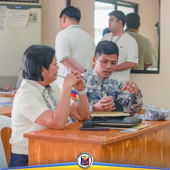 Mga kalahok sa MDRRMC meeting na nag-uusap at nagbabasa ng papeles sa mesa sa loob ng opisina