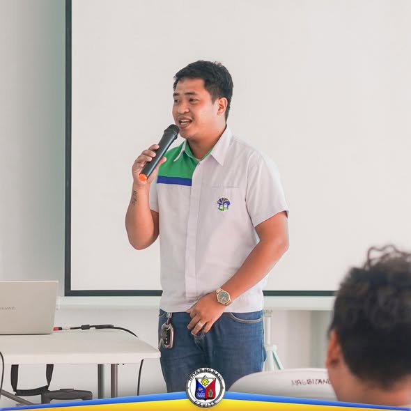 Isang lalaki na nagsasalita gamit ang mikropono sa orientation seminar ng NHA sa Naic