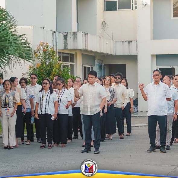 Mga kawani ng OSCA habang nagsasagawa ng flag-raising ceremony sa harap ng gusali sa Naic