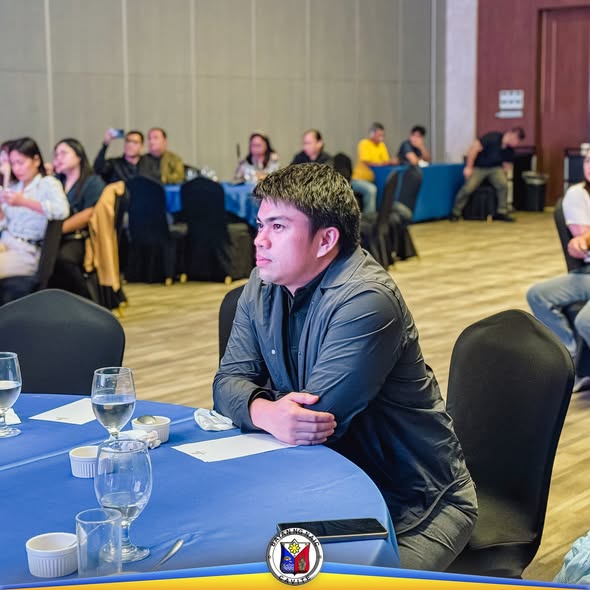 Lalaki na nakaupo sa mesa habang nanonood ng programa sa Employee's and Retiree's Recognition Night ng Naic
