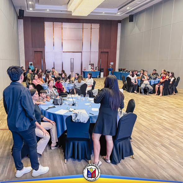 Mga kawani na nakaupo sa mga bilog na mesa habang may nakatayong tagapagsalita sa Employee's and Retiree's Recognition Night