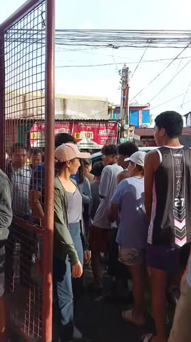 Mga tao na nakapila sa makitid na kalsada malapit sa gate habang namamahagi ng tulong sa Bancaan, Naic
