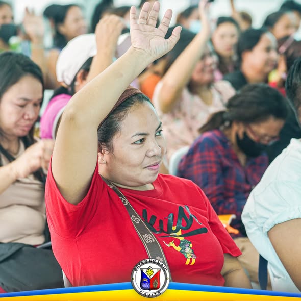 Mga dumalo sa Financial Literacy Training sa Naic, nagtataas ng kamay habang nakikinig sa loob ng hall