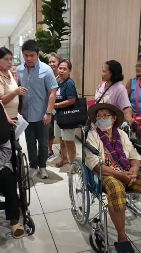 Mga senior citizen na nakaupo sa wheelchair habang naghihintay sa payout sa Waltermart Naic, Sabang
