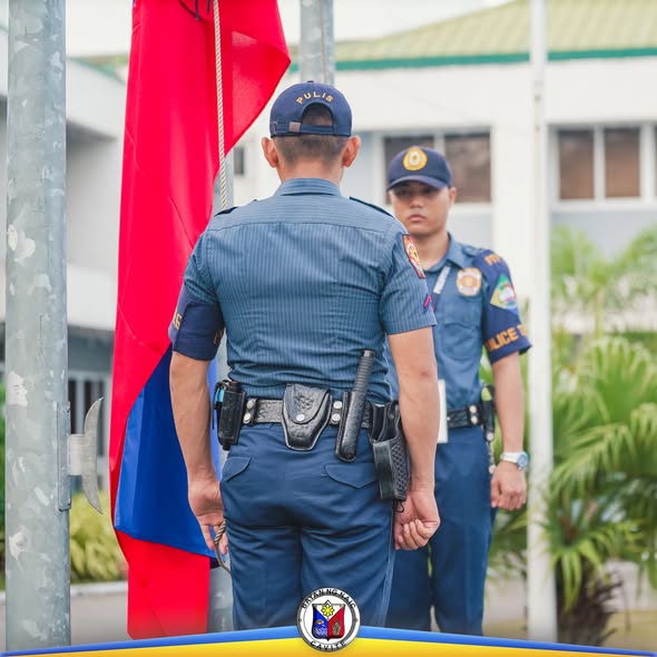 Mga pulis na nakatayo habang itinataas ang watawat sa flag raising ceremony sa Naic