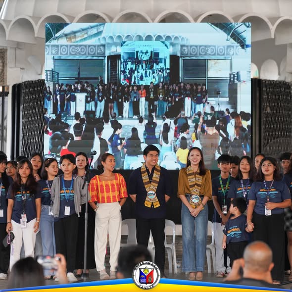 Mga kabataan at dalawang estudyanteng may sash sa entablado habang isinasagawa ang State of the Children's Address sa Naic
