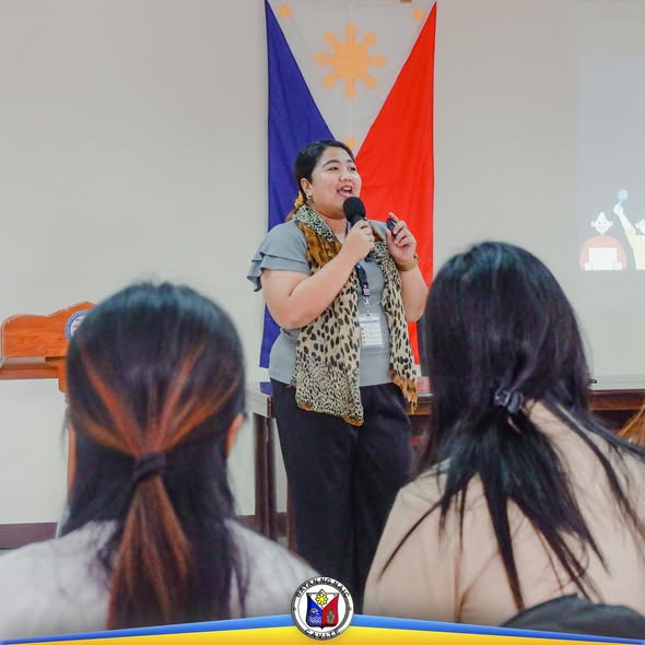 Tagapagsalita na nagsasalita sa mikropono sa harap ng mga dumalo sa Gender Sensitivity Training sa ABC Hall, Naic