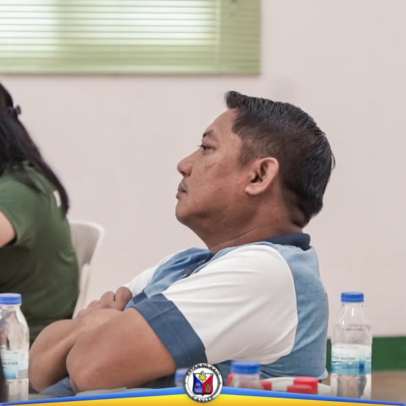 Lalaking nakaupo at nakikinig sa Local Health Board Meeting sa loob ng silid-pulungan sa Naic