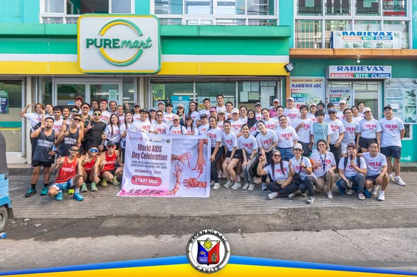 Grupo ng mga kalahok sa Fun Run para sa World AIDS Day sa harap ng PUREmart, Naic