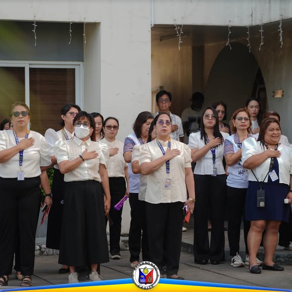 Mga kawani ng OMPDC na nakatayo at nakahawak sa dibdib habang flag raising ceremony sa Naic