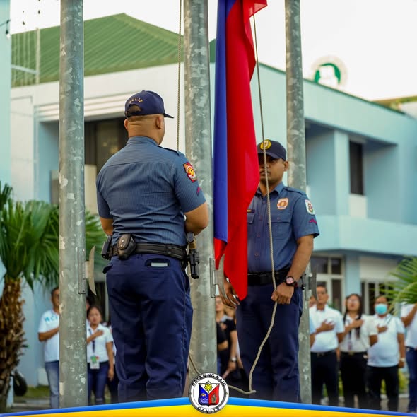 Mga pulis na nagtataas ng watawat sa flag raising ceremony sa harap ng Naic Municipal Hall