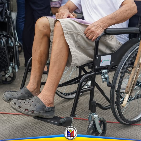 Taong nakaupo sa wheelchair habang nakikilahok sa pamamahagi ng wheelchair para sa mga PWD sa Naic