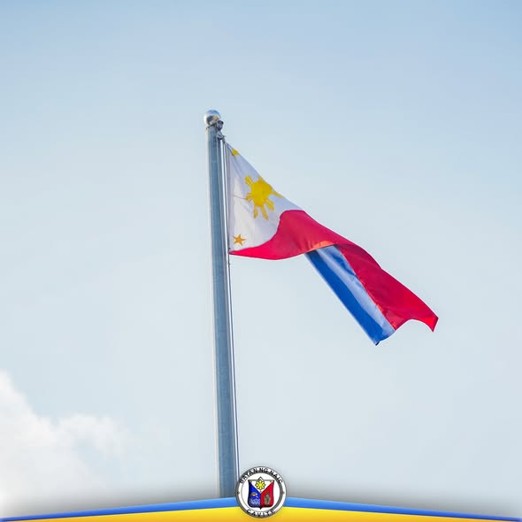 Watawat ng Pilipinas na nakawagayway sa poste laban sa asul na langit, may selyo ng bayan ng Naic