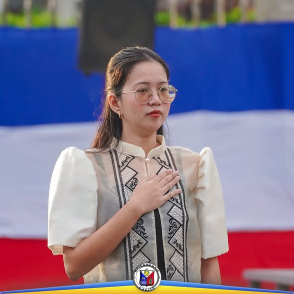 Babaeng nakalagay ang kamay sa dibdib habang nakatayo sa seremonya sa Naic Town Plaza
