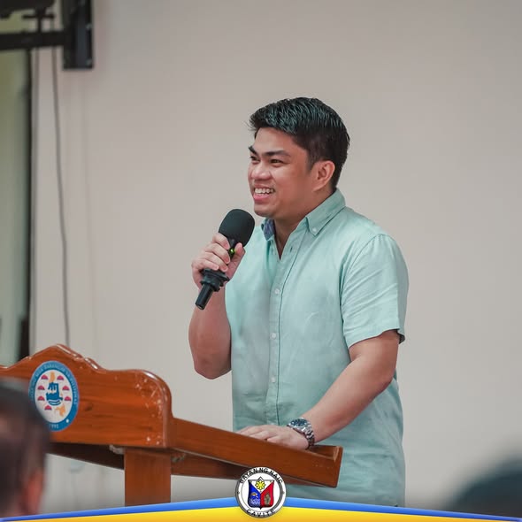 Lalaking nagsasalita gamit ang mikropono sa podium sa isang pulong ng Liga ng mga Barangay sa Naic