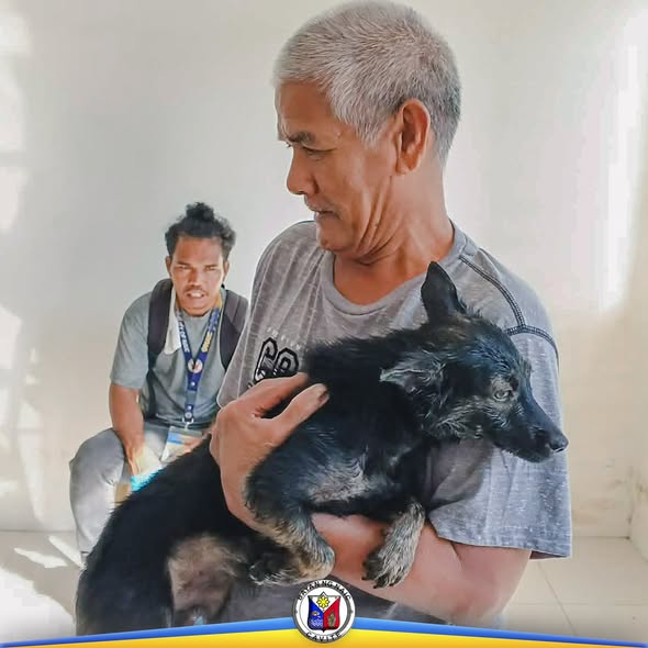 Lalaking hawak ang itim na tuta habang isinasagawa ang anti-rabies vaccination sa Barangay Balsahan