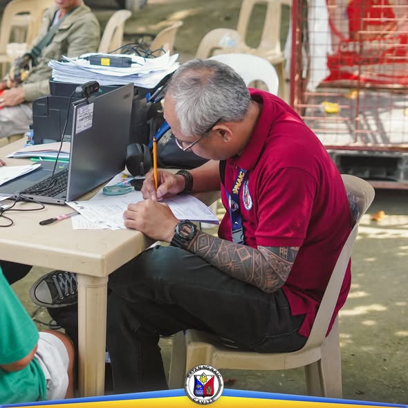Kawani habang nagsusulat ng talaan sa mesa sa Annual Farmers Registration sa Naic