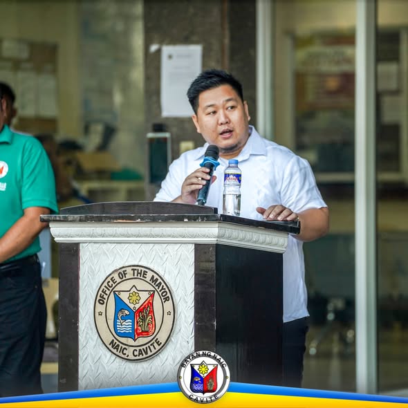 Lalaki na nagsasalita sa mikropono sa podium ng Office of the Mayor, Naic, sa lingguhang flag raising