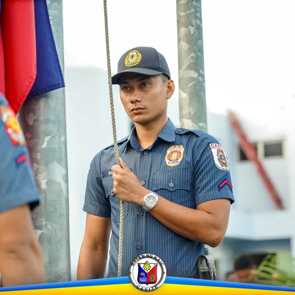 Isang nakauniporme habang hawak ang lubid ng watawat sa flag raising ceremony sa Naic
