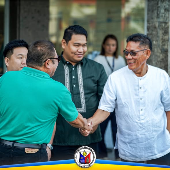 Pagkakamayan ng dalawang lalaki sa harap ng gusali habang may ilang kasamahan sa paligid