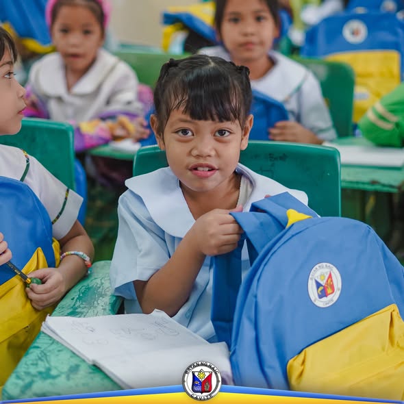 Mga mag-aaral sa silid-aralan na may bagong school bag habang tumatanggap ng suporta mula sa bayan ng Naic