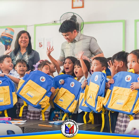 Mga mag-aaral na may hawak na school bag na asul at dilaw sa loob ng silid-aralan habang namamahagi ang pamahalaan