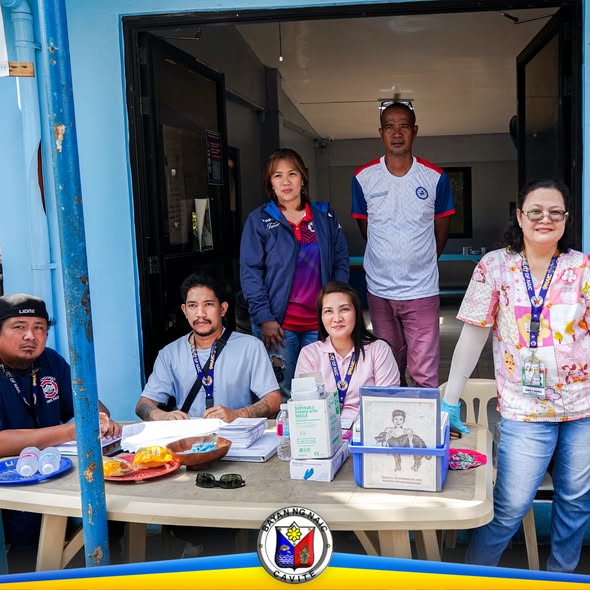 Mga kawani habang nakaupo at nakatayo sa mesa sa labas ng Barangay Capt. C. Nazareno Hall, anti-rabies vaccination