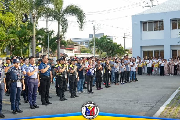 Mga kawani at mga kalahok na nakatayo sa flag raising ceremony sa harap ng gusali ng Lokal na Pamahalaan ng Naic