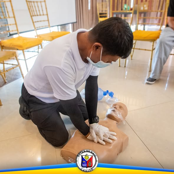 Kalahok sa BLS training na nagsasagawa ng chest compression sa CPR manikin sa loob ng hall.