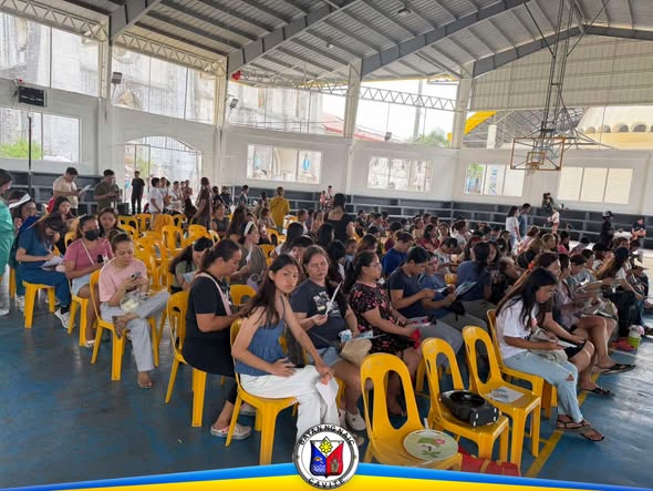 Mga kababaihang naghihintay na nakaupo sa mga upuan sa covered court habang isinasagawa ang bakuna