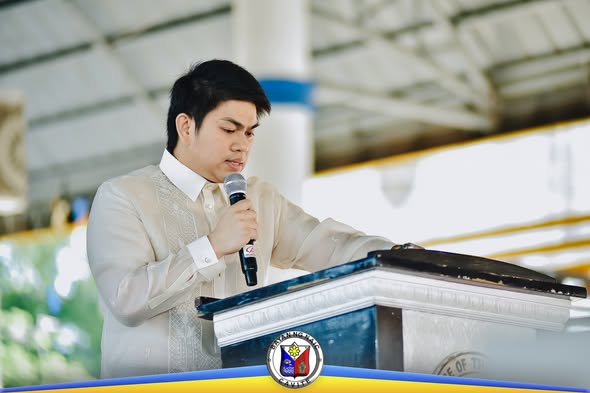 Lalaki na nagsasalita sa podium na may mikropono sa State of the Municipality Address sa Naic Town Plaza