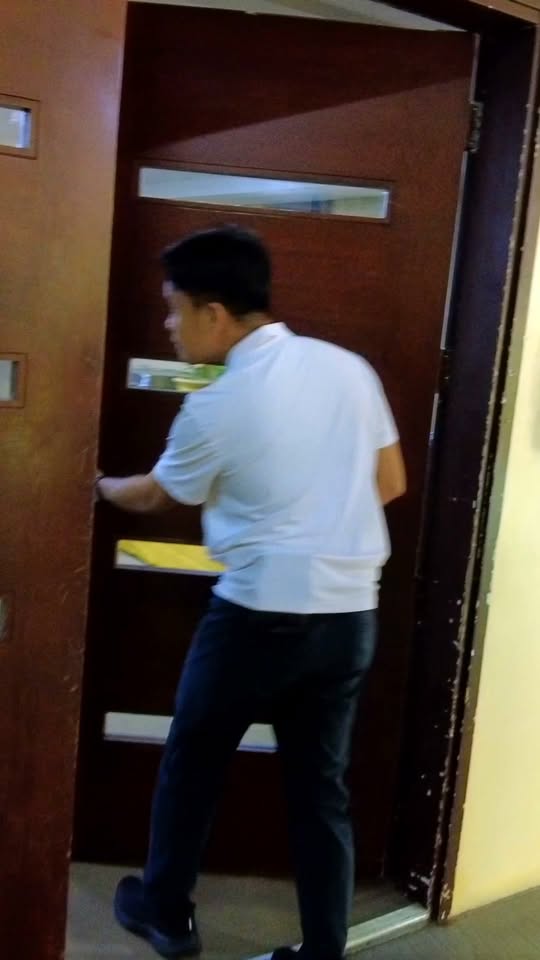 Lalaking naka-puting polo na binubuksan ang pinto ng isang gusali